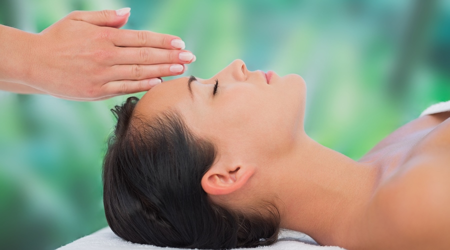 Beautiful brunette getting reiki therapy at a luxury spa