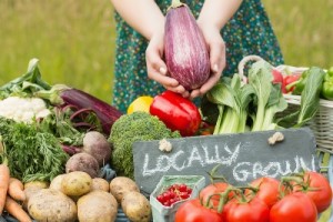 Female hands holding an aubergine above table of vegetables